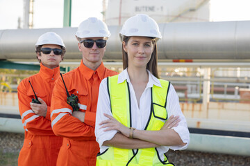 Engineers with cross arm pose at oil refinery site