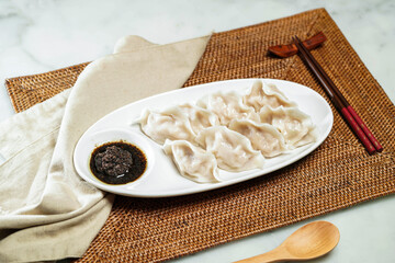 Steamed Dumplings with black truffle vinaigrette Sauce, chopsticks and spoon served in dish isolated on napkin side view of Chinese food