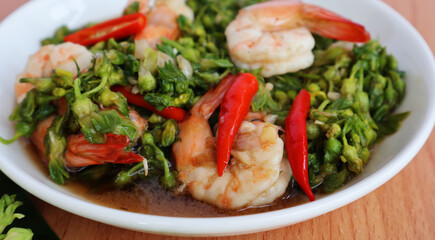 Cowslip creeper stir fry shrimp, place red chilli on top. In a white porcelain plate on the table

