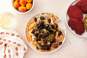 Enjoy a delightful vegetarian dish of gluten-free pasta with baked beans and zucchini, accompanied by beet pancakes with sunflower seed hummus. A perfect blend of taste and health