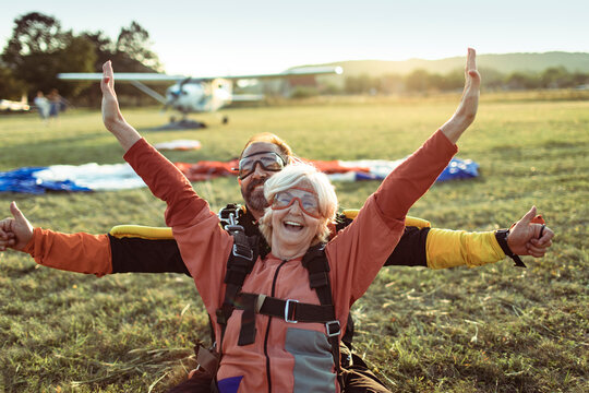 Elderly woman tandem skydiving with instructor, celebrating landing