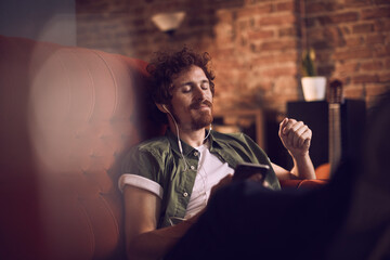 Man relaxing on couch listening to music with earphones