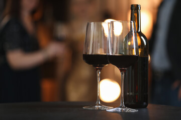 Tasty wine in glasses and bottle on black table indoors, selective focus