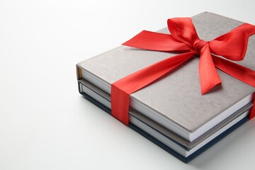 Books tied with red ribbon on white background, closeup. Space for text