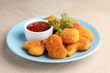 Tasty chicken nuggets with chili sauce and parsley on wooden table