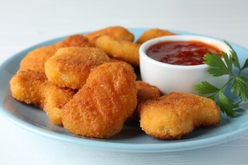 Tasty chicken nuggets with chili sauce and parsley on white table, closeup