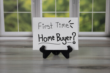 First Time Home Buyer? Handwritten on white canvas sitting on black easel in- front of a window.