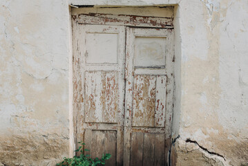 old vintage wooden door in crumbling wall, crack in wall, crumbling plaster