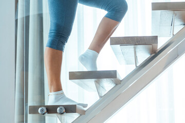 Woman in sportswear exercising by climbing stairs at home to stay fit, emphasizing the importance...