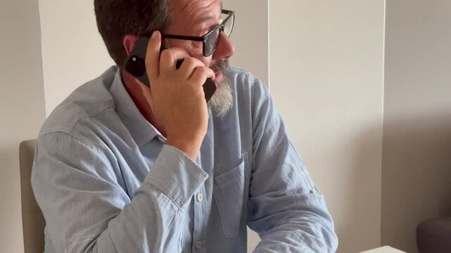 Busy mature man office worker manager consulting client by telephone checking information on laptop screen. Professional teleworker broker salesman offer goods services remotely using phone laptop