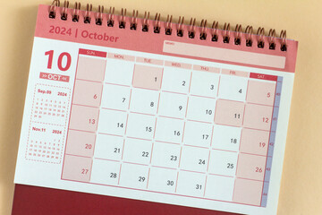 Desk calendar for October 2024 on a beige background.