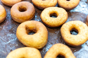 Donuts ready to be decorated with icing, donut production process.