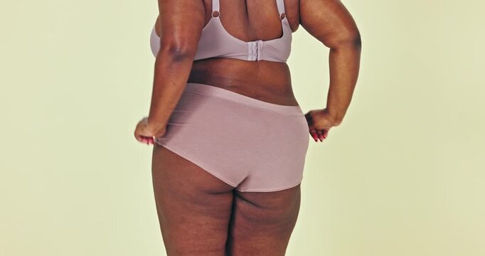 Dancing, body positivity and butt of woman in underwear in a studio for self love celebration. Health, wellness and bum of young African female model moving with confidence by green background.