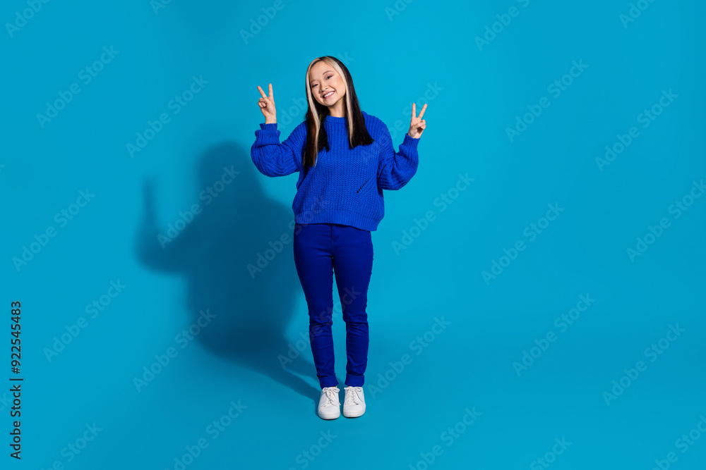 Sticker Full length body photo funny youngster trendy girl in fall season outfit and white sneakers showing v sign isolated on blue color background