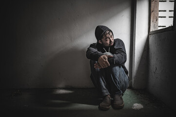 Asian man addict drug in the deserted place,A junkie feels alone in this world,Sad young man sitting in the corner of the room,People are stressed and have depression