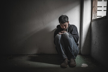 Asian man addict drug in the deserted place,A junkie feels alone in this world,Sad young man sitting in the corner of the room,People are stressed and have depression