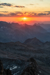 Paisaje montañoso durante el amanecer con sol delante.