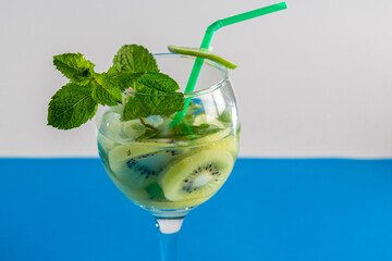Glass with fruit cocktail kiwi mint lime with ice on blue background