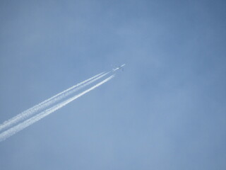 Jet tearing through the blue sky with a huge trail. Airplane at high altitude with contrail.