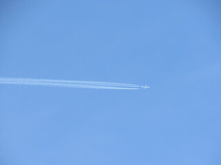 Jet tearing through the blue sky with a huge trail. Airplane at high altitude with contrail.