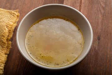 Thick meat broth with spices in a bowl on a wooden table