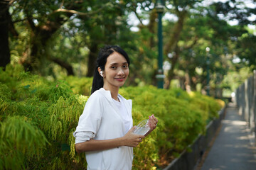 Asian woman resting after drinking and listening to music in the park