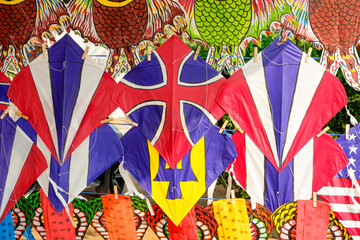 Fototapeta premium Colorful fancy paper kites with national flag and animal pattern hanging for sale on shelf display in the walking street market at Thailand