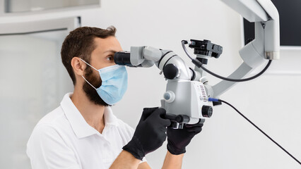 Highly qualified bearded male dentist using modern technologies in dental treatment, complicated...