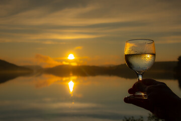 Glass of wine at sunset on the edge of a lake in the Canadian forest in Quebec
