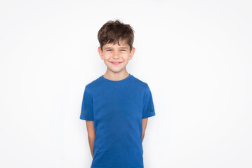 A young boy in a blue T-shirt on a white background is smiling sincerely, his naive smile is very beautiful. An 8-year-old boy is very happy because parents love him