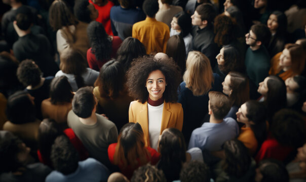 Smiling young woman with curly hair stands out confidently in a crowd, drawing attention amidst a sea of people