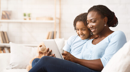 Happy Loving Family. Cheerful african american mom and daughter browsing internet using digital tablet. Free space