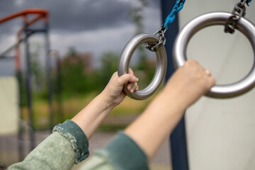 woman hands grasp metal gymnastic rings, symbolizing strength, dedication, and the pursuit of...