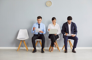 Diverse job candidates sitting on office chairs in row, business people waiting for job interview,...
