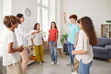 Group of school children in casual wear standing in circle with female friendly woman teacher or...