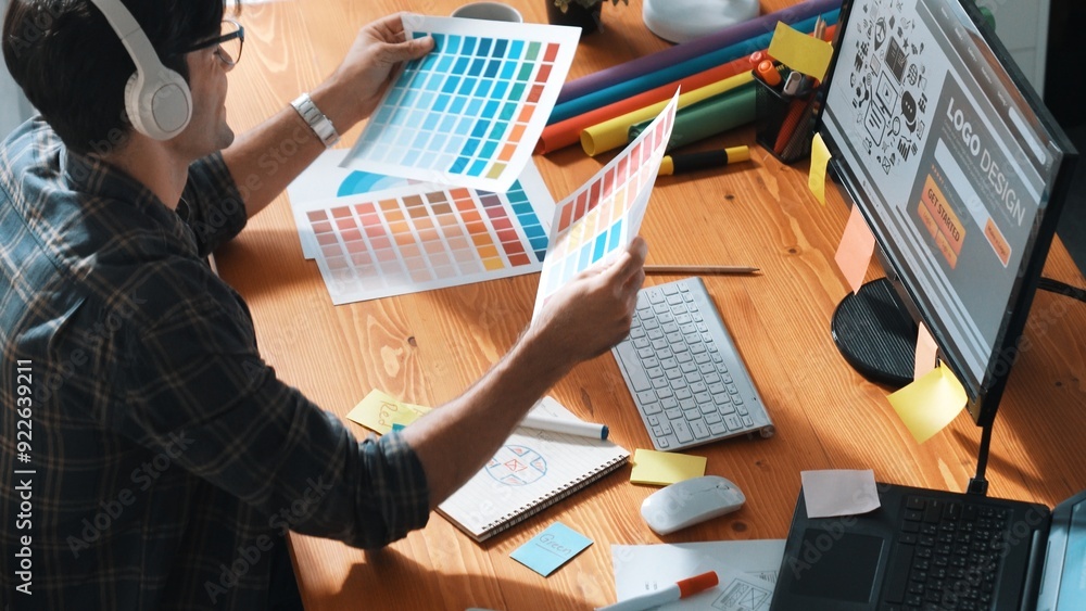 Poster interior designer looking at laptop and designing color while looking at palette at meeting table wi