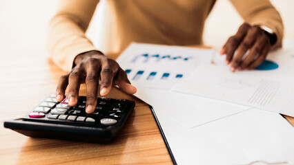 Budget Planning. Unrecognizable black businessman using calculator, tracking income and expenses....