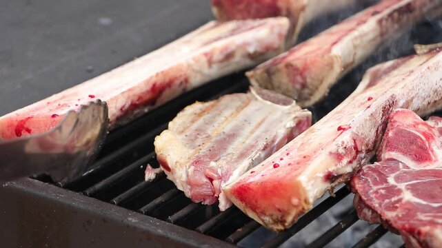 corte de carne cocinandose de un lado y tuetanos crudos