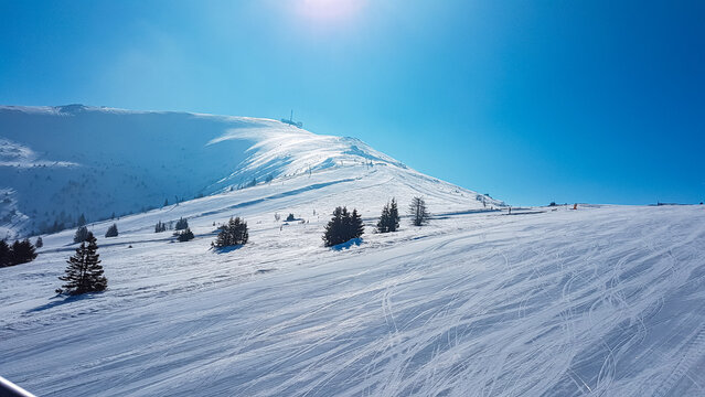 Panoramic view of ski resort Koralpe in Lavanttal, Carinthia Styria, Austria. Winter wonderland in Austrian Alps. Well prepared ski slopes in high alpine terrain. Sunny day with blue sky. Skiing trip