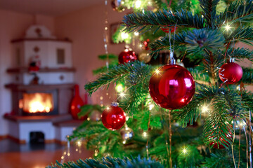 Christmas ball on fir tree branch and blur burning fireplace .