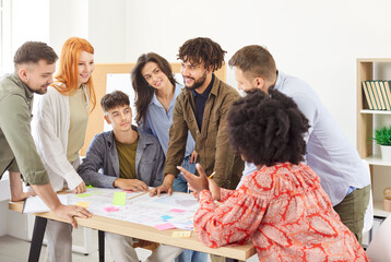 Obraz premium Diverse group of young business people company employees in casual clothes discussing job projects talking in office making great decisions with brainstorming. Coworkers working together at workplace