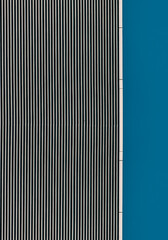 striped wall of a gray tall building against a blue clear sky