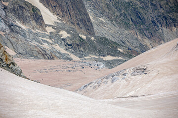 View of a glacier in the alps whose snow is covered with brown sahara sand 