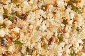 Close-up of the ingredients for a traditional Spanish cod omelette before the eggs are added, showing the vibrant colors and rich textures of flaked codfish, diced onions, and green bell pepper.