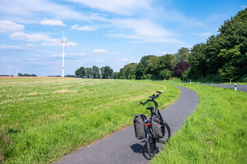 Trekking bike with paniers at a bending road through the fields of the German countryside around...