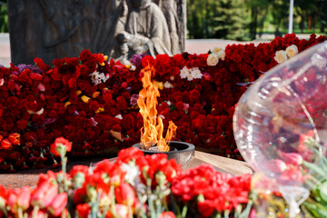 Eternal flame in the middle of red carnations and different colors, Victory Day holiday on May 9th...