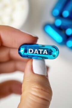 Close-up of a hand holding a blue capsule labeled 'DATA' against a blurred background.