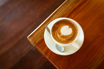 Hot coffee latte with latte art milk foam in cup mug on wood desk on top view. As breakfast In a coffee shop at the cafe,during business work concept,vintage style