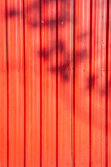 Red or orange old corrugated metal with Shadow of a branch texture surface sheet for industrial building background, copy space text or design