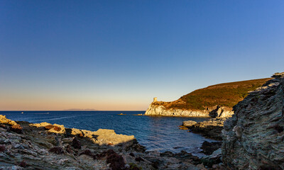 Naklejka premium Genoese Agnello tower at sunset, Barcaggio, Cap Corse, Corsica, France. Capraia Isola, Italian island, in background.